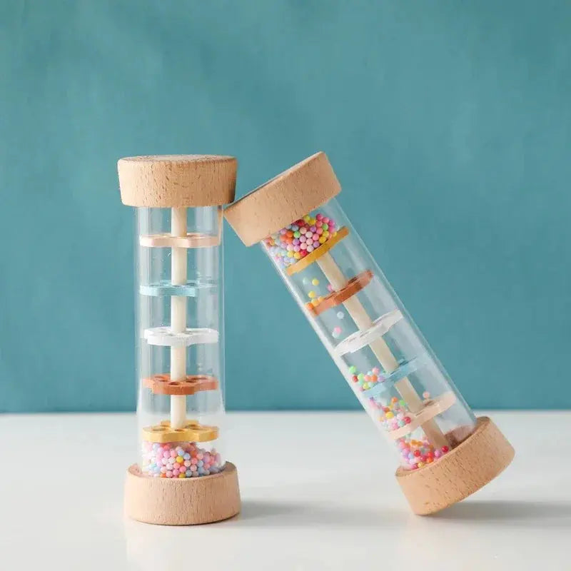 Two glass tubes with wooden lids filled with colorful beads on a white surface and teal background