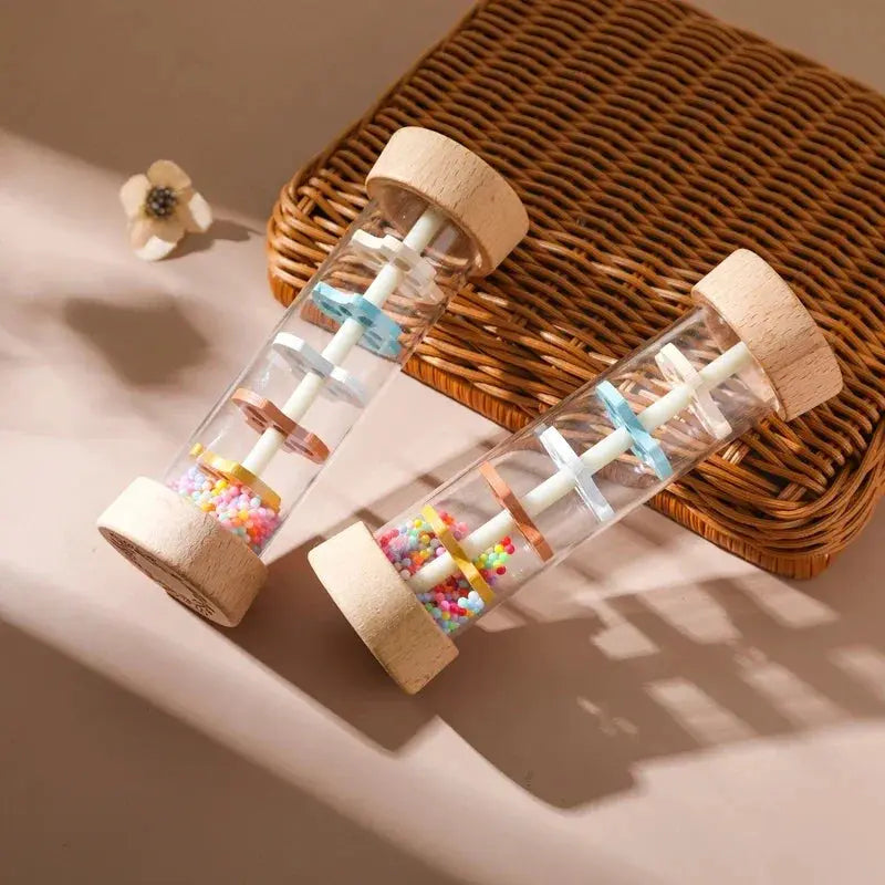 Two glass bottles with wooden lids containing colorful beads on a woven surface.