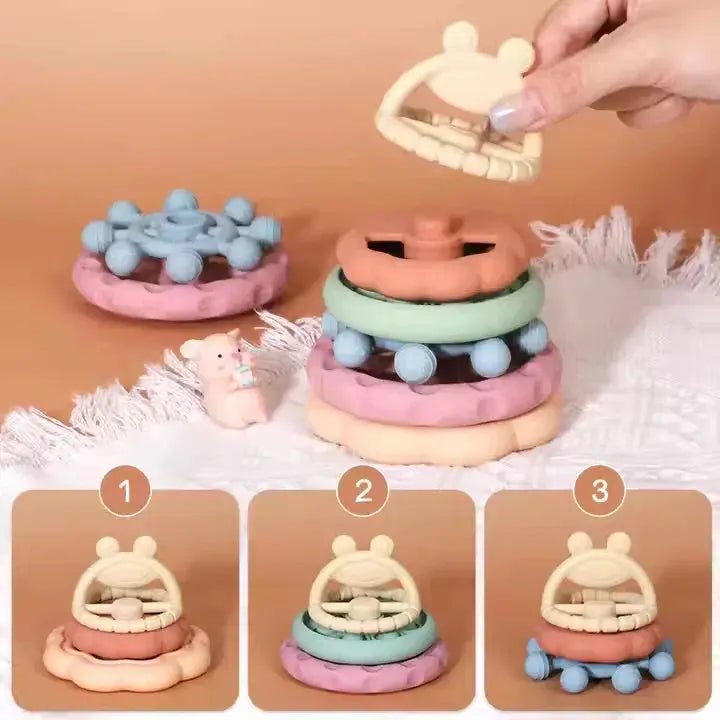 Stackable baby toys with a hand demonstrating assembly on a beige background