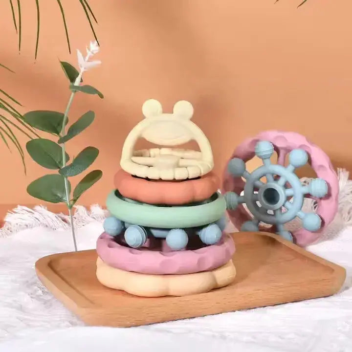Colorful baby teething ring set on a wooden board with a plant in the background